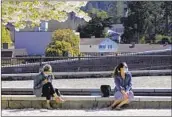  ?? GILLIAN FLACCUS AP ?? Oregon residents wearing masks sit in downtown Lake Oswego. Oregon officials are looking to keep mask mandates in place.