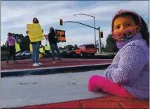  ?? RAY CHAVEZ STAFF PHOTOGRAPH­ER ?? Stella Rodriguez, 4, rests as her mother Adrienne, left, and Lulu Guzman hold up signs during a rally to reopen Gilroy schools at Santa Teresa Boulevard and Highway 152 in Gilroy on Wednesday.