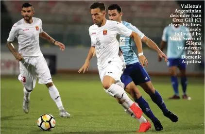  ??  ?? Valletta's Argentinia­n defender Juan Cruz Gill (C) clears his lines closely followed by Mark Scerri of Sliema Wanderers Photo: Domenic Aquilina