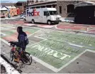  ?? ALBERT CESARE/USA TODAY NETWORK ?? Robert Thomas stops on a bicycle near the Black Lives Matter mural on Plum Street on Friday. Last June, 70 artists to design and paint a Black Lives Matter mural downtown.