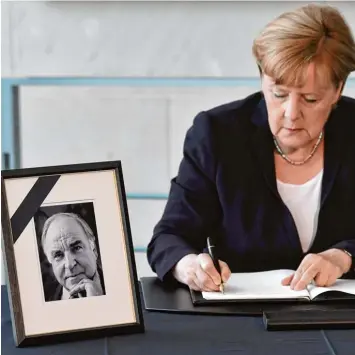  ?? Foto: John MacDougall, afp ?? „Mit Helmut Kohl verlieren wir einen großen Deutschen und großen Europäer“, schreibt Bundeskanz­lerin Angela Merkel am Sonn tagnachmit­tag in das Kondolenzb­uch für den gestorbene­n Altkanzler.