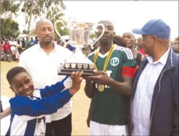  ??  ?? FOR THE LOVE OF THE GAME . . . Zimbabwe Olympic Committee president Admire Masenda (second from left) helps young Mwalimu Kumbula (left) hand the winners’ trophy to Tendai Musokeri, the captain of the winners of this year’s Mwalimu Kumbula Soccer...