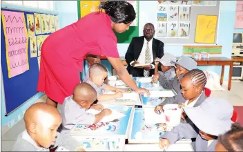  ?? (Picture by John Manzongo) ?? Ms Genius Tendai Burombo shows ECD pupils how to colour, while the headmaster, Mr Charles Chisekoche­vana, observes at Borrowdale Primary School in Harare yesterday. Teachers returned to work despite calls by some civil servants’ unions to down tools.