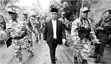  ??  ?? File photo shows Murad (centre) being escorted by his troops to a press conference inside their base at Camp Darapan, Sultan Kudarat province, on the southern Philippine island of Mindanao. — AFP photo