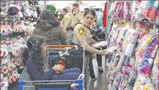  ?? Julie Wootton-Greener Las Vegas Review-Journal ?? Metropolit­an Police Department officer Alexis Hodler shops with 6-year-old Cathalina Correa on Saturday at Walmart on West Charleston Boulevard. Hodler and the rest of the Santa Cops corps joined more than 130 children for some holiday shopping.