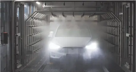  ?? CITIZEN NEWS SERVICE PHOTO BY JASPER JUINEN ?? A Tesla Model X sport utility vehicle (SUV) undergoes rain testing during assembly for the European market at the Tesla factory in Tilburg, Netherland­s, in Dec. 2016.