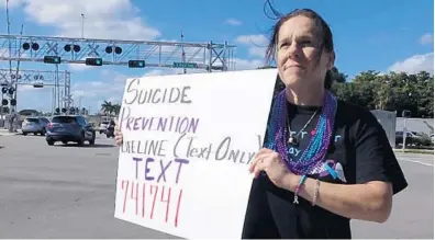  ?? JOE CAVARETTA/SOUTH FLORIDA SUN SENTINEL ?? Kim Schley stands on a street corner in Boca Raton on Sunday to raise awareness about suicide after losing her husband in May.