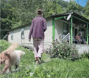  ??  ?? Sheila McGlothlin walks home in her pyjamas after checking the mail in Virginia’s former coal country.