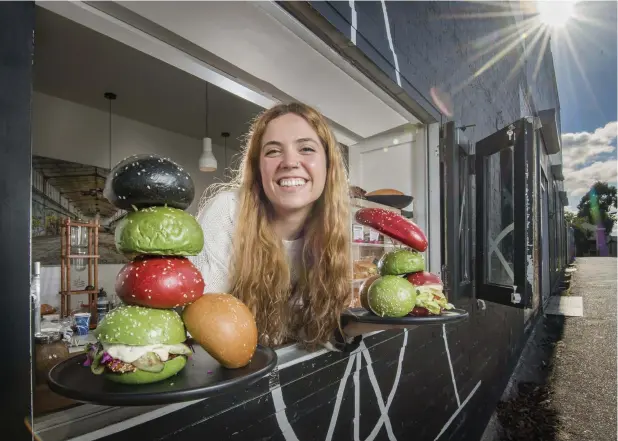  ??  ?? BETTER BE-LOAF IT: Beatriz Ribeiro, 25, with Too Many Chiefs cafe's new coloured burger bun, made with 50 per cent raw vegetables. Picture: JASON EDWARDS