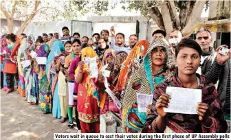  ??  ?? Voters wait in queue to cast their votes during the first phase of UP Assembly polls