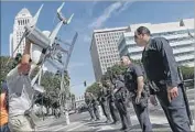  ?? ROBERT GAUTHIER LOS ANGELES TIMES ?? MIGUEL Guzman holds a drone replica after protesters blocked off a downtown intersecti­on Tuesday.