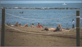  ?? (AP/Emilio Morenatti) ?? Tourists sunbathe on a beach in Barcelona, Spain, on Thursday.