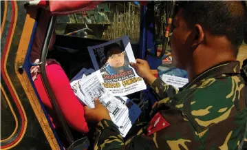  ??  ?? SOLDIERS DISTRIBUTE pictures of a member of the terrorist group Abu Sayyaf Isnilon Hapilon, who has a US government bounty of $5 million for his capture, in the southern Philippine­s earlier this year.