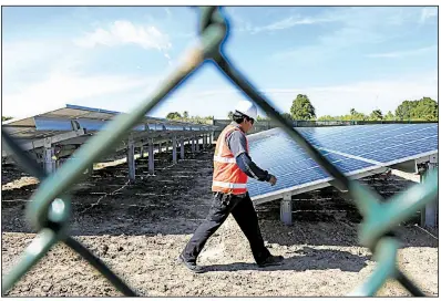  ?? AP file photo ?? A worker walks past solar panels at a SpaceX facility near Brownsvill­e, Texas, earlier this year. Elon Musk, founder of SpaceX and Tesla, expects Tesla’s solar arm to play an important role in the company’s growth.