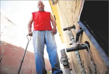  ?? Genaro Molina
Los Angeles Times ?? BRUCE SMITH looks at the broken water line on the side of his Long Beach apartment. At the thousands of buildings in the city with fewer than four units, such as this one, no routine inspection­s occur.