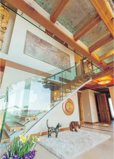  ??  ?? A floating staircase with glass walls leads to a loft area. Saanichton architect Silvia Bonet says staircases are a golden opportunit­y for a homeowner, builder or designer to create a striking visual element.