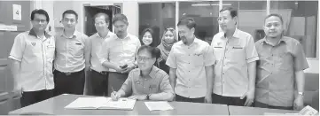  ??  ?? Julaihi (seated) signs the guestbook at Sibuti District Office.