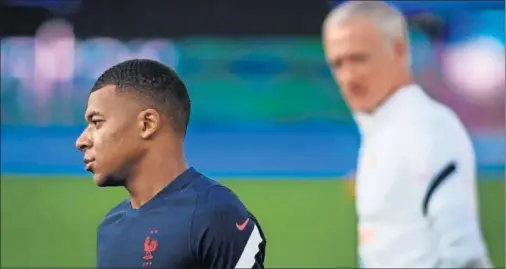  ??  ?? Didier Deschamps observa a Mbappé durante un entrenamie­nto de la selección francesa.