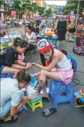  ??  ?? Street vendors are allowed after 7 pm every day in Yibin’s East Street, Sichuan province. A chic girl has her nails done by a manicurist.