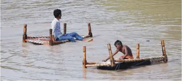  ?? Agence France-presse ?? ±
People sit on a cot in a flooded area after water levels of Yamuna River increased, in New Delhi, on Wednesday.