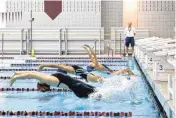 ??  ?? Kingfisher’s Jaryn Frey, Bartlesvil­le’s Haley Downey and Midwest City’s Rachel Cook compete Monday in the girls 100-yard backstroke during the 2016 All State Swim Meet at Jenks High School.