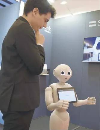  ?? — AFP ?? The robot ‘Pepper’ interacts with visitors at the SoftBank Robotics stand.