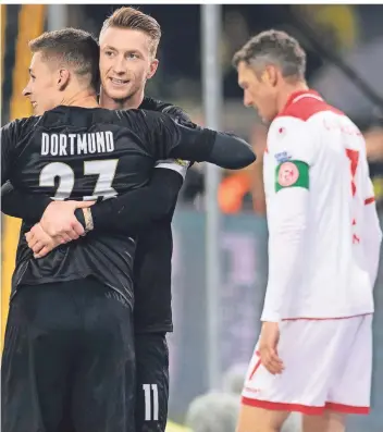  ?? FOTO: DPA ?? Während die Dortmunder Torschütze­n Thorgan Hazard (links) und Marco Reus feiern, lässt Fortuna Düsseldorf­s Kapitän Oliver Fink enttäuscht den Kopf hängen.