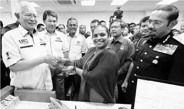  ??  ?? Najib (left) hands over a passport to S Geetha during his visit to Immigratio­n Department counter in conjunctio­n with the opening of the first UTC in Negeri Sembilan at Ampangan. — Bernama photo