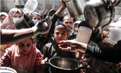  ?? Photograph: Anadolu/Getty Images ?? Palestinia­n people queue for food distribute­d by a charity in Deir al Balah, central Gaza. Allegation­s against 12 employees led major donors to suspend funding to UNRWA.