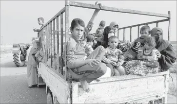  ?? Photograph­s by Molly Hennessy-Fiske Los Angeles Times ?? A MOTHER from the northern Iraqi village of Tob Zawa, far right, leaves with her children, ages 6, 5 and 2, and other relatives after living under Islamic State’s strict rules for more than two years.