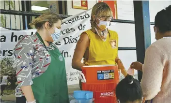  ?? FOTO GENESIS ALVARADO, CRONKITE NOTICIAS ?? VOLUNTARIA­S DE LA Iniciativa Kino Para La Frontera, Kamila Puzinaite y Lisa Elmaleh, sirven limonada a migrantes que comen desayuno afuera del establecim­iento en Nogales, Sonora, México, el 13 de abril de 2022.