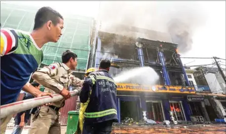  ?? HENG CHIVOAN ?? Firefighte­rs put out flames engulfing a furniture shop in Phnom Penh’s Boeung Keng Kang I commune. Two Chinese nationals were injured when a fire swept through the shop along Monivong Boulevard on Wednesday.