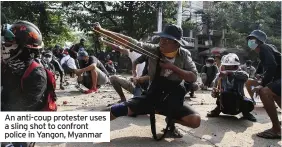  ??  ?? An anti-coup protester uses a sling shot to confront police in Yangon, Myanmar