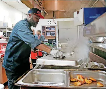  ?? [PHOTOS BY BRYAN TERRY, THE OKLAHOMAN] ?? Chef Corey Harris prepares food at Off the Hook’s south Oklahoma City location.