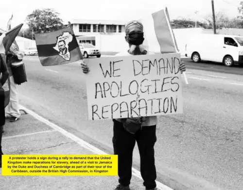  ?? ?? A protester holds a sign during a rally to demand that the United Kingdom make reparation­s for slavery, ahead of a visit to Jamaica by the Duke and Duchess of Cambridge as part of their tour of the Caribbean, outside the British High Commission, in Kingston