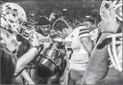  ?? The Associated Press ?? EGG ‘DOGS: Mississipp­i State quarterbac­k (7) and offensive lineman Elgton Jenkins celebrate Thursday with the Egg Bowl Trophy after the Bulldogs’ 35-3 victory over the Ole Miss Rebels on Thanksgivi­ng in Oxford, Miss.