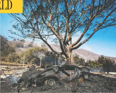  ?? APU GOMES/AFP VIA GETTY IMAGES ?? A destroyed car is seen as fire continues to burn near the Brentwood area, just west of Beverly Hills, on Monday. The wildfire broke out early Monday near the renowned Getty Center in Los Angeles, forcing widespread evacuation­s.