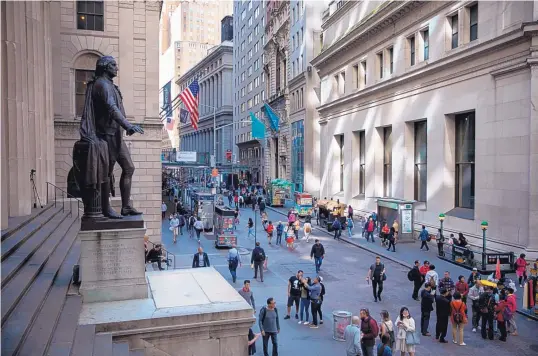  ?? MACHAEL NAGLE/BLOOMBERG ?? Pedestrian­s walk along Wall Street near the New York Stock Exchange in May 2019.