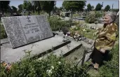 ?? CZAREK SOKOLOWSKI — THE ASSOCIATED PRESS FILE ?? A woman stands near a mass grave and a monument in the village of Chlaniow, Poland, on June 19, 2013 that holds the bodies of Poles killed in a 1944attack on the village by the Nazi SS-led Ukrainian Self Defense Legion.