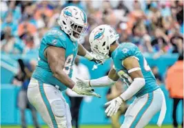  ?? ERIC ESPADA/GETTY ?? Dolphins’ Christian Wilkins (94) celebrates with teammate Nik Needham (40) after sacking Bengals quarterbac­k Andy Dalton on Dec. 22 at Hard Rock Stadium in Miami Gardens.