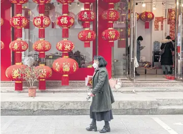  ?? ©2023 THE NEW YORK TIMES ?? A woman walks past shops decorated for the Chinese Lunar New Year in Yiwu, China recently.