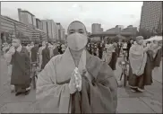  ?? AP-AHN Young-joon ?? Buddhists monks wearing faces masks to help protect against the spread of the new coronaviru­s pray to celebrate the Buddha’s birthday at the Gwanghwamu­n Plaza in Seoul, South Korea, on Thursday.