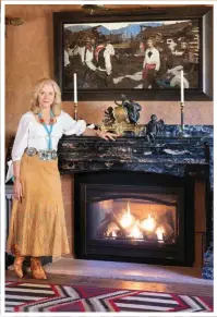  ??  ?? Naoma Tate stands in front of The Enchanted Hill, 1924, oil on canvas, by Dean Cornwell (1892-1960). A bronze sculpture of a cherub sits on the mantle. A circa 1900 Navajo Third Phase Chief’s Blanket is on the floor.