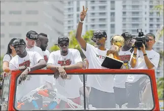  ?? ALAN DIAZ/ THE ASSOCIATED PRESS ?? Chris Bosh holds the NBA championsh­ip trophy while riding with Heat teammates in a parade to honor the repeat champs Monday in Miami. An estimated 400,000 people lined the streets for the celebratio­n.