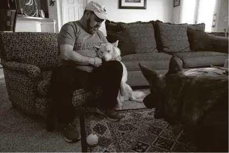  ??  ?? Arroyo plays with his dogs Odin, left, and Bear at home in Pflugervil­le. He is angry he had to fight over the bill for his 50-mile transfer as he recovers from COVID-19. “If you’re going to save lives, you can’t screw the people you’re saving,” he says.