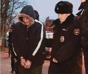  ?? REUTERS PIC ?? Policemen escorting a man, suspected of organising and carrying out a bombing in a supermarke­t, outside a court building in St Petersburg, Russia, on Sunday.