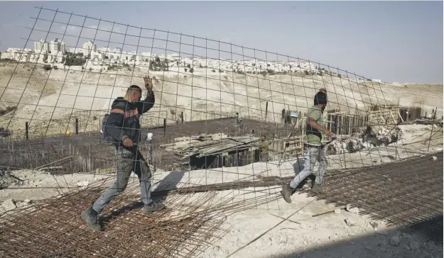  ?? PICTURE; AP ?? 0 Constructi­on workers carry materials at a constructi­on site in the West Bank settlement of Maaleh Adumim