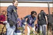  ?? ALYSSA POINTER / ALYSSA.POINTER@AJC.COM ?? Youth minister Jonathan Mitchell (left) reacts as a Dacula middle schooler gets the hang of shoveling dirt during a school beautifica­tion event Oct. 19 at Dacula Middle School.