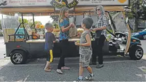  ?? Kathryn Scott, Special to The Denver Post ?? The Veggie Van’s Shelly Cook, right, gives fresh produce to some of her younger customers at a stop in Arvada this month.