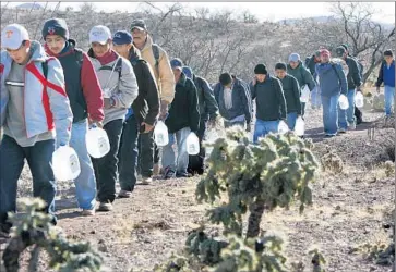  ?? Don Bartletti
Los Angeles Times ?? IMMIGRANTS FOLLOW a smuggler in Arizona in 2007. The worst year for border-crossing fatalities since the Pima County Medical Examiner’s Office began collecting data was 2010, when 223 bodies were found.